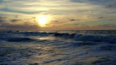 Büyüleyici günbatımı güzel bir şekilde okyanus dalgalarını aydınlatıyor dramatik bulutlarla nefes kesici bir sahne yaratıyor.