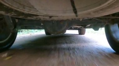 Engebeli çakıllı bir yolda aracın altından büyüleyici bir atış sahnenin dinamik hareketini gösteriyor.