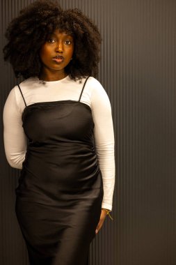 Zarif siyah elbisesi ve beyaz bluzu olan kendine güvenen bir kadın. Moda ve modern görünüş fotoğrafta yer alıyor.