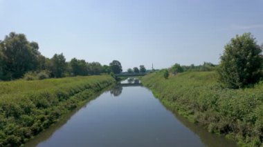 Berrak ve sakin bir nehir manzarası. Berrak mavi gökyüzünün altında yemyeşil bir yer.
