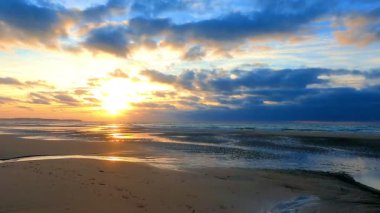 Sakin ve sakin sahili aydınlatan nefes kesici bir gün batımı. Nazik dalgalarla birlikte, gerçek güzellikleri gözler önüne seriyor.
