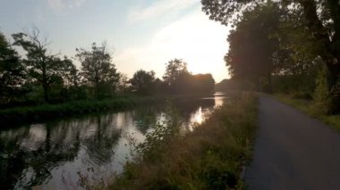 Gün batımında huzurlu ve huzurlu bir kanal yolu, doğanın inanılmaz güzelliğini ve sükunetini güzel bir şekilde yansıtıyor.