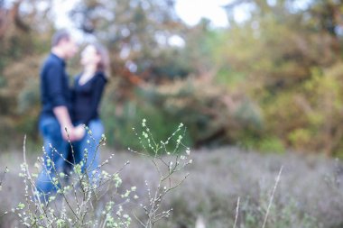 Bir çift, canlı doğayla çevrili sakin bir doğa ortamında sevgi dolu bir şekilde el ele tutuşuyor.