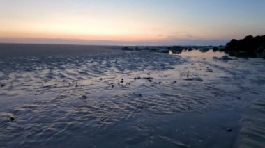 Gün batımında resim gibi ve sakin bir sahil manzarası. Güzelce sergilenen nazik dalgalar ve sakin bir ufuk.