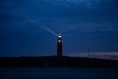De Cocksdorp, Texel, Hollanda, 27 Ekim 2024, güzel çarpan bir deniz feneri akşam gökyüzüne güçlü bir ışık huzmesi yayar, tekneleri güvenli bir şekilde eve götürür.