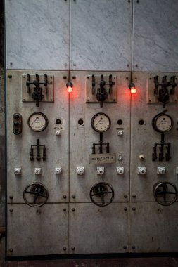 Çeşitli göstergeler, göstergeler ve parlak kırmızı göstergeler gösteren antika bir retro kontrol paneli.