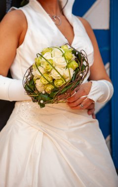 Enfes bir gelinlik içindeki zarif bir gelin zarif duruşu olan modern, yaratıcı bir çiçek buketi tutuyor.