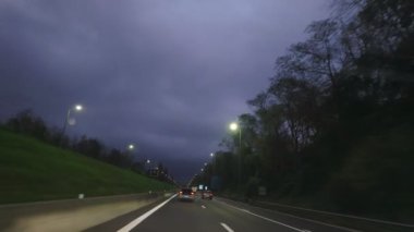 Alacakaranlıktaki uzun bir otoyolun sakin ve huzurlu manzarası karamsar bulutların ortasındaki sokak lambalarıyla güzelce aydınlatılmış.