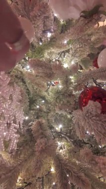 Renkli süsler ve parlayan ışıklarla süslenmiş bir Noel ağacının çarpıcı manzarası şenlikli bir ortam yaratıyor.