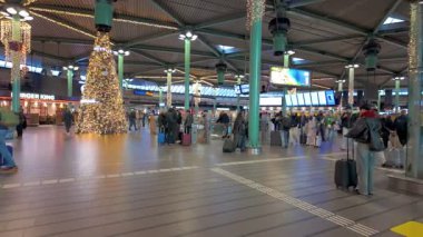 Schiphol Havaalanı, Amsterdam, Hollanda, 20 Aralık 2024 modern tasarım, gezginler ve bayram süslemeleri ile hareketli bir havaalanı terminali.