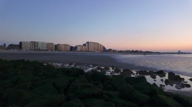 Nieuwpoort, Batı-Flanders, Belçika, 6 Ekim 2024, sakin bir sahil manzarası, parlak renkli bir gökyüzüne karşı canlı bir şehir silüeti sergiliyor.
