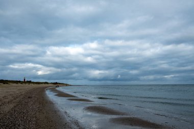Eierland, De Cocksdorp, Texel, Hollanda, 28 Ekim 2024, sakin bir sahil manzarası bulutlu gökyüzünün altında hafif dalgaların kıyıya vuruşunu gösteriyor.