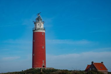 Eierland, De Cocksdorp, Texel, Hollanda, 28 Ekim 2024, çarpıcı kırmızı bir deniz feneri durgun, berrak mavi gökyüzüne karşı gururla duruyor.