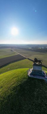 Napolyon Savaş Alanı, Waterloo, Walloon Brabant, Belçika, 4 Mart 2025 görkemli bir aslan heykeli, yemyeşil alanlar ve açık mavi gökyüzünün yer aldığı nefes kesici bir manzara.