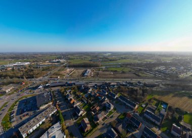 Yalancı, Antwerp, Belçika, 5 Mart 2025, göz kamaştırıcı bir hava manzarası açık mavi gökyüzü altında yemyeşil manzaralı kentsel konutlar sergiliyor.