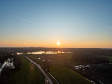 Engin tarlalar ve sakin su üzerindeki nefes kesici ve nefes kesici günbatımı doğanın derin sükunetini vurguluyor.