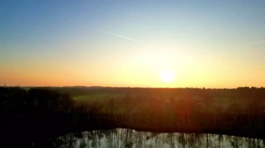 Sersemletici bir günbatımı, sakin bir manzaraya canlı renkler yayar. Suyu güzelce yansıtır.