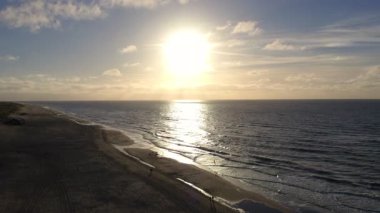 Çarpıcı bir günbatımı, sakin okyanusa sıcak bir parıltı saçar. Güzelce yansıtan doğası zarif güzelliği.