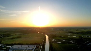 Bereketli tarlaları ve kıvrımlı bir nehri aydınlatan güzel bir gün doğumunun nefes kesici hava manzarasını deneyimleyin.
