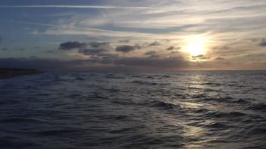 Gün batımının sakin manzarası okyanus dalgalarını ve gökyüzünü güzelce aydınlatıyor, nihai rahatlama için mükemmel.