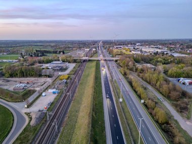 E19 Breda-Antwerp, Brecht, Antwerp, Belçika, 8 Nisan 2025, çarpıcı bir hava manzarası dolambaçlı bir otobanı ve alacakaranlıktaki yemyeşil manzarayı güzel bir şekilde gösteriyor.