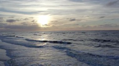 Sakin okyanus dalgalarını yansıtan muhteşem bir günbatımının nefes kesici görüntüsünü deneyimleyin, sakin projeler için ideal.