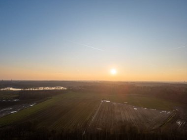 Şaşırtıcı derecede güzel bir gün doğumu engin tarlaları aydınlatıyor, suyun üzerinde büyüleyici yansımalar yaratıyor.