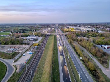 E19 Breda-Antwerp, Brecht, Antwerp, Belçika, 8 Nisan 2025, şehir altyapısıyla iç içe geçmiş güzel bir otoyol ve demiryolu manzarası.