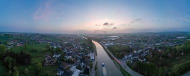 Lot, Beersel, Vlaams-Brabant, 22 Nisan 2025, gün batımında bereketli kırsalda süzülen sakin bir nehir manzaralı güzel bir hava manzarası.
