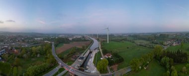 Lot, Beersel, Vlaams-Brabant, 22 Nisan 2025, Havadan bakıldığında dolambaçlı bir otoyol, uzun rüzgar türbinleri ve yemyeşil bir hava görünüyor.