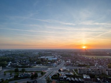 Nefes kesici güzellikte bir gün batımı dramatik bir gökyüzü altında huzurlu ve resimsel bir kasaba manzarasına ılık renkler döküyor.