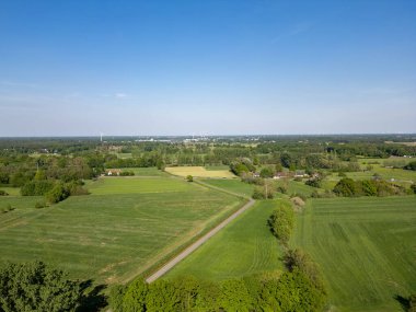 Enfes bir hava manzarası canlı yeşil alanlar ve berrak mavi gökyüzünün altında geniş bir açık arazi.