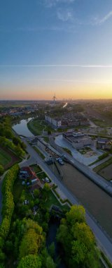 Halle, Vlaams Brabant, Belçika, 27 Nisan 2025 günbatımında sersemletici yemyeşil manzaralar arasında süzülen sakin bir nehri gözler önüne seriyor.