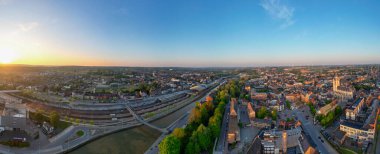 Halle, Vlaams Brabant, Belçika, 27 Nisan 2025, nefes kesici bir hava manzarası güneş doğarken canlı bir şehir yakalıyor, çarpıcı güzelliğini ve çeşitli manzaralarını sergiliyor.