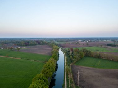 Rijkevorsel, Antwerp, Belçika, 27 Nisan 2025, Genişleme alanları ve hafif dolambaçlı bir nehir, alacakaranlıkta sakin bir kırsal alan oluşturmak için birleşir.