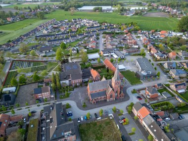 Sint Jozef, Rijkevorsel, Antwerp, Belçika, 27 Nisan 2025, çarpıcı bir hava perspektifi yeşil tarlaları ve tarihi bir kilisesi olan sakin bir köyü büyüleyici bir şekilde gösteriyor.