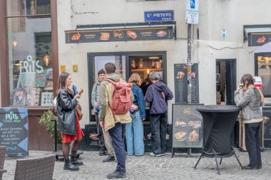 Melkmarkt, Antwerp, Antwerp, Belçika, 26 Nisan 2025, hareketli ve hareketli bir sokak manzarası müşterilerin popüler bir yerel yemek yerinde eğlendiklerini gösteriyor.