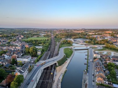 Halle, Vlaams Brabant, Belçika, 6 Mayıs 2025, nefes kesici bir hava manzarası demiryolu rayları ve sakin su yolu ile dolu canlı bir şehir manzarası sergiliyor.