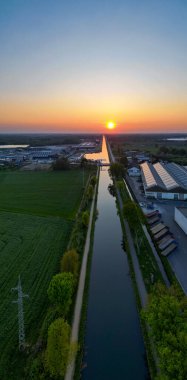 Rijkevorsel, Antwerp, Belçika, 27 Nisan 2025 büyüleyici ve canlı gün batımı yemyeşil yemyeşil ile çevrili sakin ve sakin bir kanala güzel bir şekilde yansıyor.