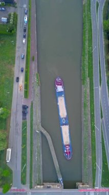 Lot, Beersel, Vlaams-Brabant, 22 Nisan 2025, yemyeşil otlaklar ve karayollarının yanındaki bir kargo mavnasının çarpıcı hava görüntüsü..