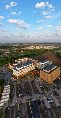 Colruyt, Wilgenveld, Halle, Vlaams Brabant, Belçika, 13 Mayıs 2025, canlı yeşil manzaralar ve güzel açık gökyüzünün ortasındaki modern bir hastanenin çarpıcı hava manzarası.
