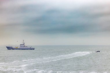 Den Helder, Hollanda, Ekim 28, 2024, güzel sakin bir kıyı manzarası uzak mesafede büyük bir gemi ve sürat teknesi gösteriyor.