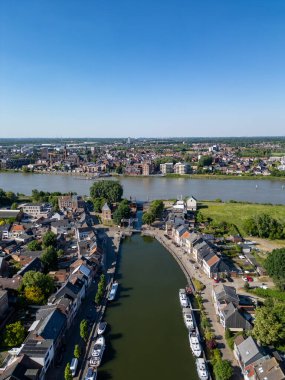 Klein-Willebroek, Willebroek, Antwerp, Belçika, 13 Mayıs 2025, nefes kesen bir hava manzarası temiz mavi gökyüzünün altında büyüleyici bir kasabanın içinden süzülen huzurlu bir nehri gösteriyor.