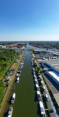 Klein-Willebroek, Willebroek, Antwerp, Belçika, 13 Mayıs 2025 'te, açık mavi gökyüzüne karşı uzanan çeşitli teknelerle çevrili huzurlu bir kanal görüntüsü yakaladı.