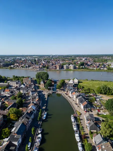 Klein-Willebroek, Willebroek, Antwerp, Belçika, 13 Mayıs 2025, nefes kesen bir hava manzarası temiz mavi gökyüzünün altında büyüleyici bir kasabanın içinden süzülen huzurlu bir nehri gösteriyor.