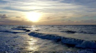 Çarpıcı bir günbatımı okyanus dalgalarını aydınlatır. Huzuru ve doğanın büyüleyici güzelliğini somutlaştırır.