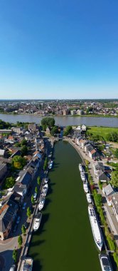 Klein-Willebroek, Willebroek, Antwerp, Belçika, 13 Mayıs 2025, çarpıcı bir hava fotoğrafı, güzel evler ve canlı yeşilliklerle çevrili sakin bir kanal yakalıyor.