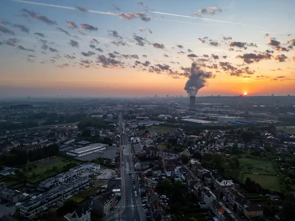Bergensesteenweg, Sint-Pieters-Leeuw, Brüksel, Belçika, 13 Mayıs 2025, nefes kesen bir gün batımı manzarası çarpıcı şehir manzaralarını ve girdap gibi endüstriyel duman bulutlarını ortaya çıkarıyor.