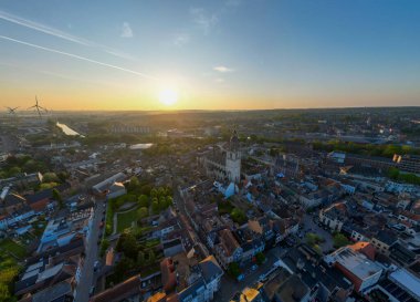 Halle, Vlaams Brabant, Belçika, 27 Nisan 2025, nefes kesici bir hava fotoğrafı günbatımında çarpıcı bir şehir manzarasını güzel bir şekilde yakalıyor, canlı renkler sergiliyor.