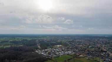 Çarpıcı bir hava görüntüsü, dramatik ve bulutlu bir gökyüzünün altında manzaralı bir kırsal alanı güzel bir şekilde gösteriyor.